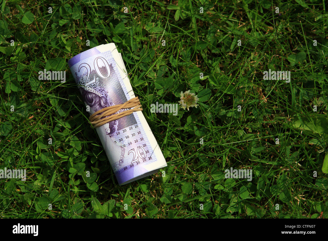 Sterling Notizen aufgerollt in einem Gummiband, liegend auf dem Rasen Stockfoto