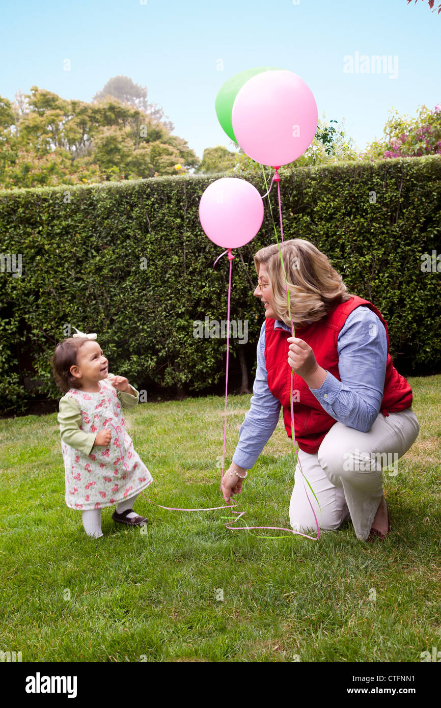 Frau und kleine Mädchen auf der Wiese mit bunten Luftballons. Stockfoto