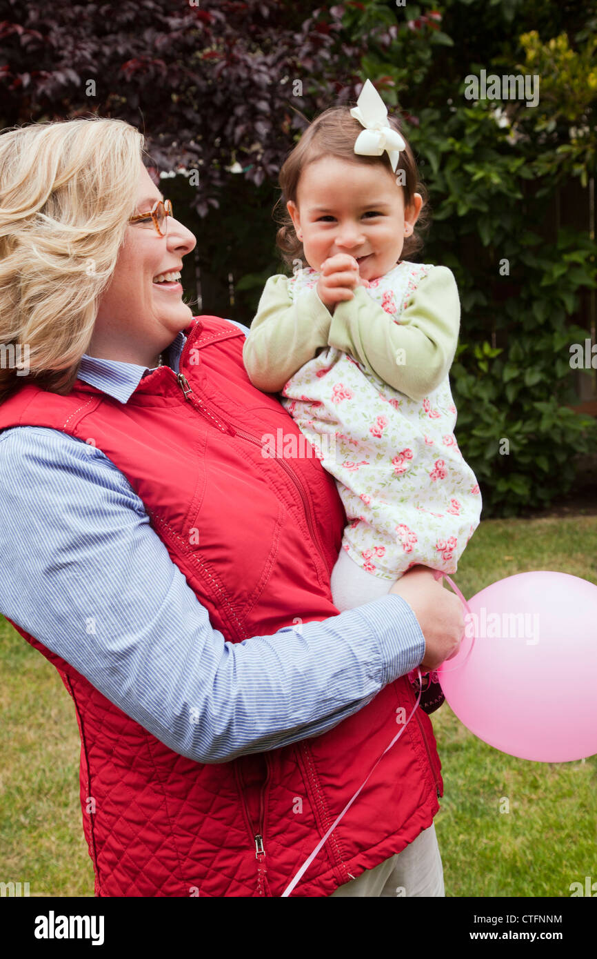 Eine Frau hält ein kleines Mädchen und sie haben einen rosa Ballon. Stockfoto