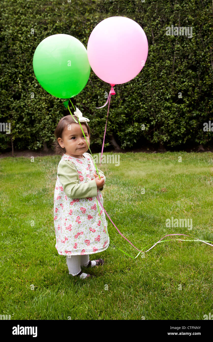 Kleines Mädchen mit einem rosa und einem grünen Ballon. Stockfoto