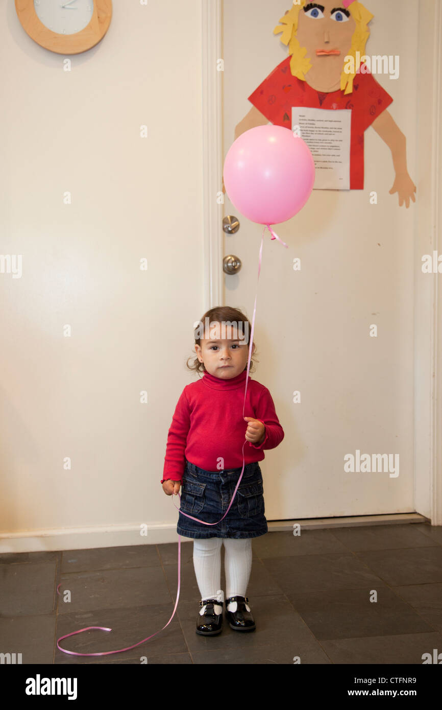 Ein kleines Mädchen in das Haus einen Ballon halten. Stockfoto