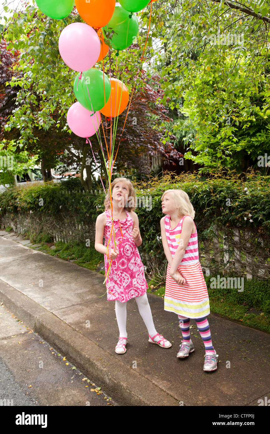 Zwei Mädchen sind auf der Straße mit bunten Luftballons. Stockfoto