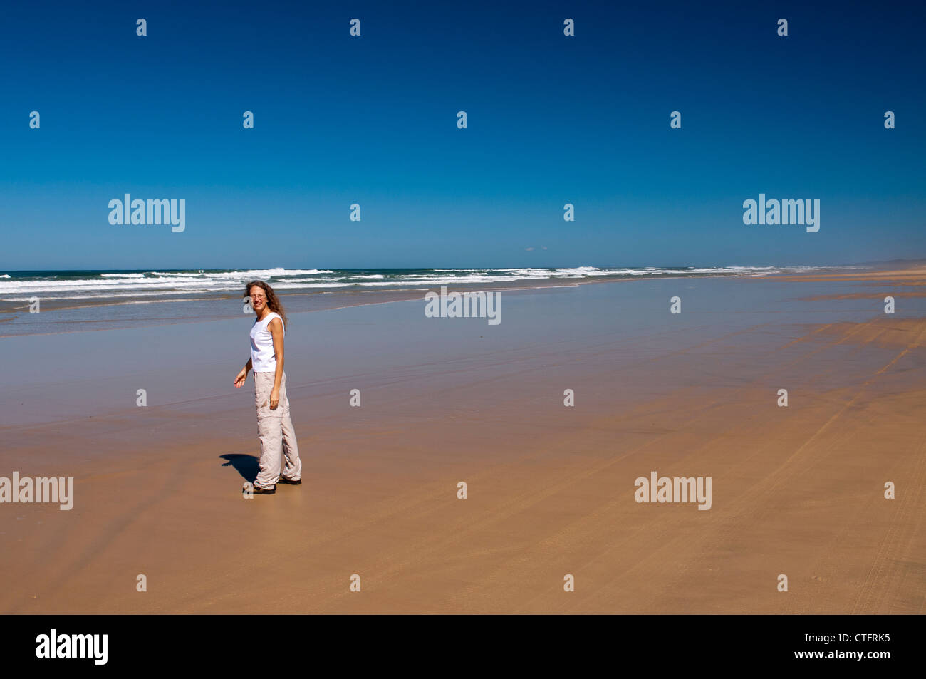 Frau allein an einem Strand an einem sonnigen Tag. Stockfoto