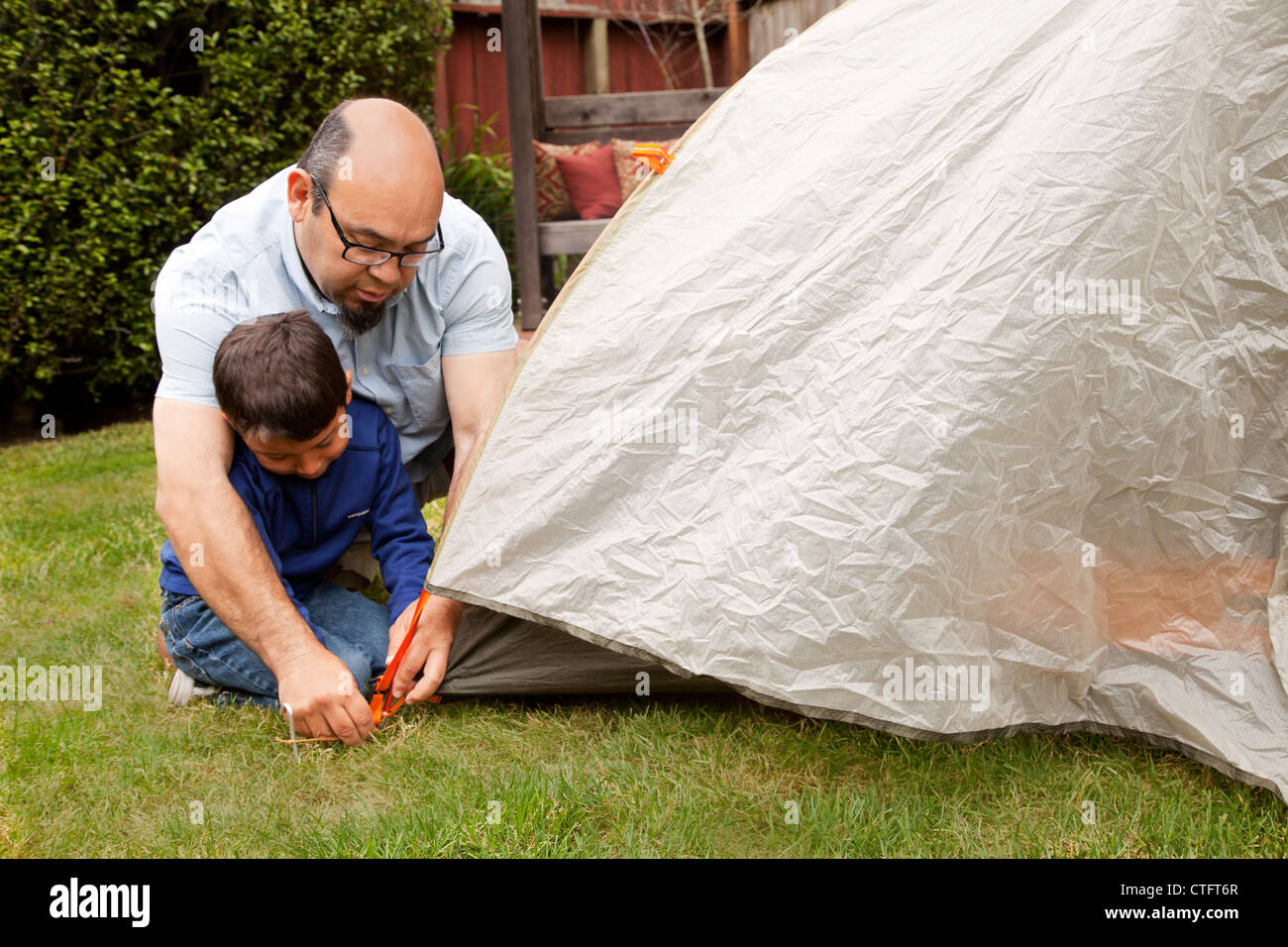 Vater trägt dazu bei, dass sein Sohn ein Zelthering zu sichern. Stockfoto