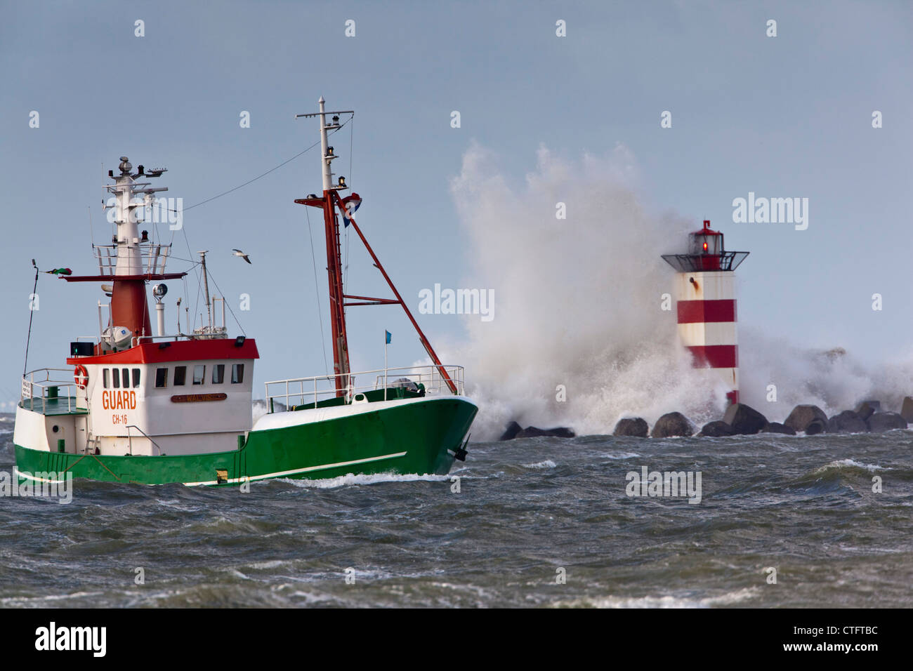 Die Niederlande, IJmuiden, Sturm. Wellen gegen Leuchtturm oder Leuchtfeuer. Schiff. Stockfoto