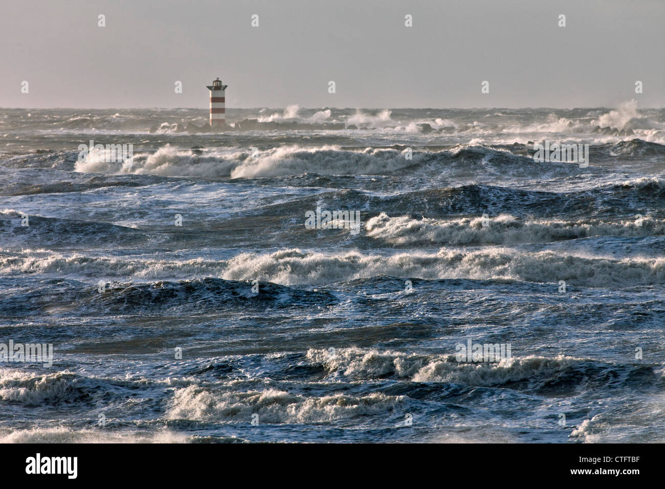 Die Niederlande, IJmuiden, Sturm. Wellen gegen Leuchtturm oder Leuchtfeuer. Stockfoto