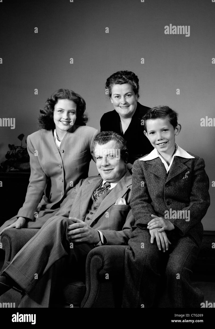 1940ER JAHRE PORTRAIT FAMILIE MUTTER VATER TOCHTER SOHN SITZEN ZUSAMMEN AUF STUHL STUDIO Stockfoto