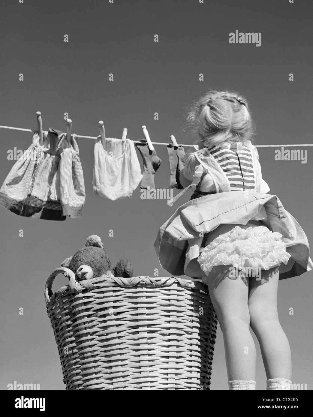 1950ER JAHRE RÜCKSEITE DES MÄDCHEN HÄNGT WÄSCHE WIND BLOWING ROCK  GEKRÄUSELTE HÖSCHEN ZEIGEN Stockfotografie - Alamy