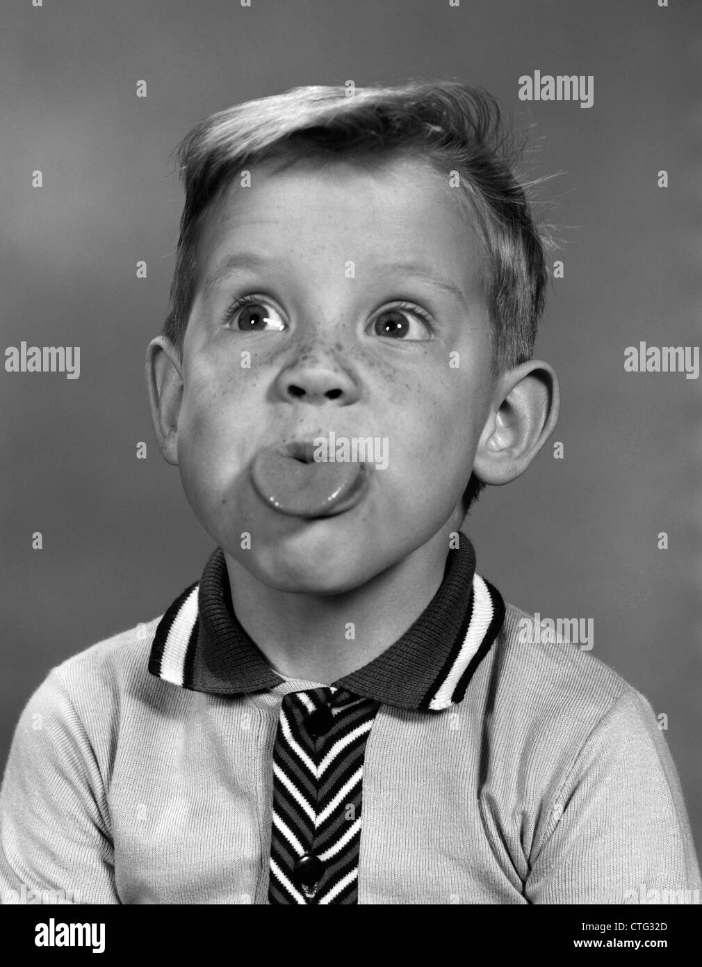 1960ER JAHRE PORTRAIT JUNGE MIT BLONDEN HAAREN & SOMMERSPROSSEN, DIE ZUNGE HERAUS Stockfoto