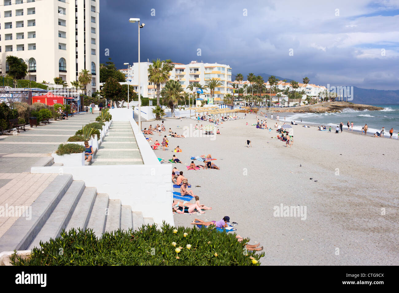 Menschen, die zum Sonnenbaden am Sandstrand im Resort Stadt Nerja, Costa Del Sol, Andalusien, Spanien. Stockfoto