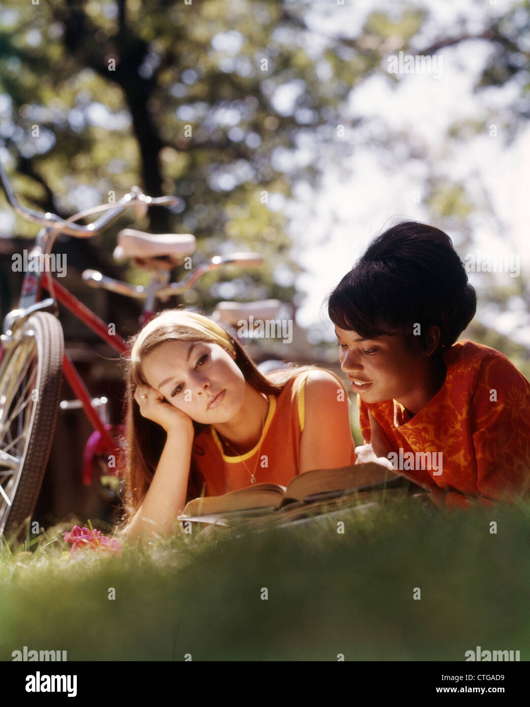 1970ER JAHREN ZWEI COLLEGE-STUDENTINNEN LIEGEN AUF GRÄSER MIT BÜCHER LESEN LERNEN Stockfoto