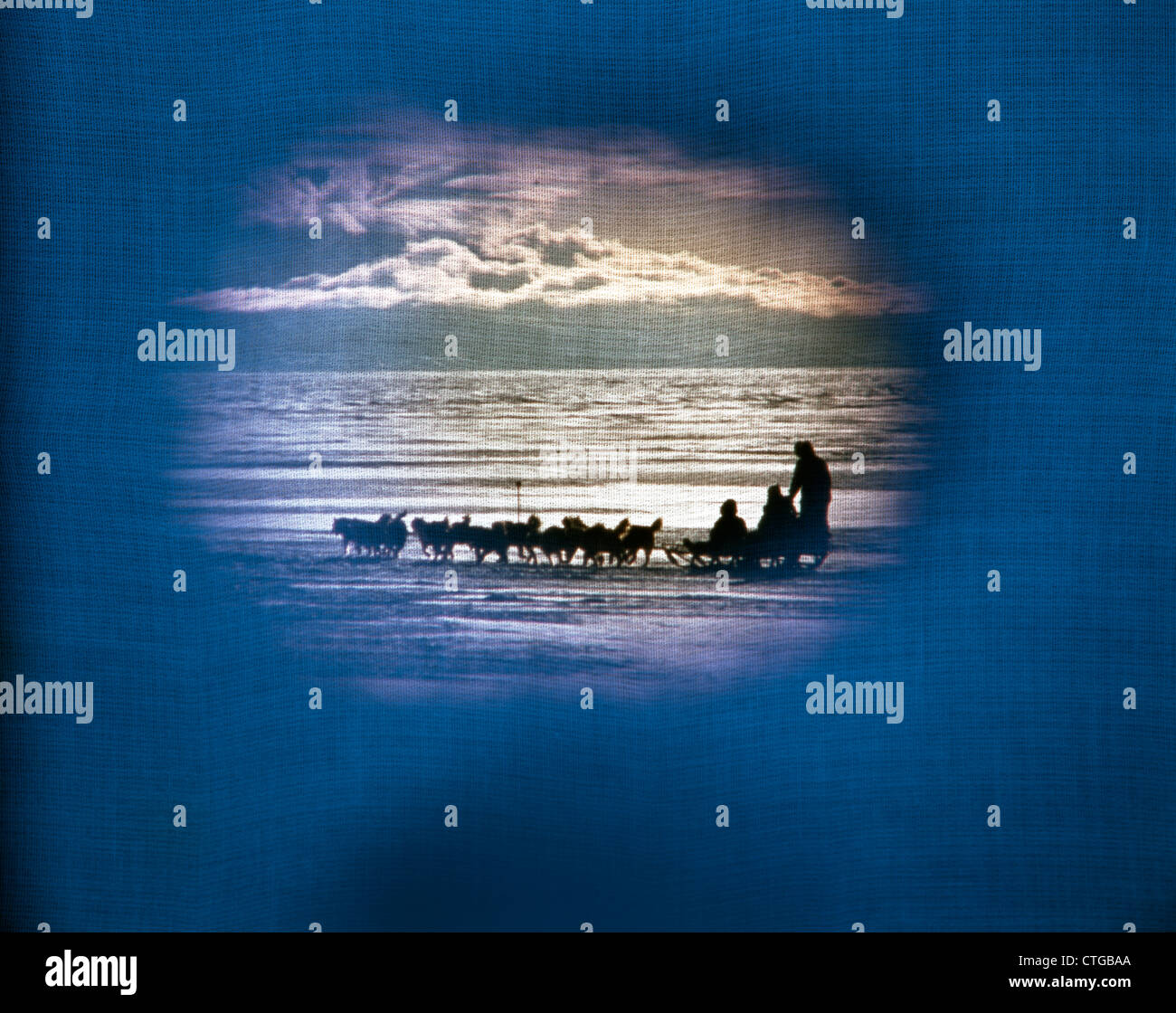 1970ER JAHREN VIGNETTE DREI PERSONEN HUNDESCHLITTEN BLAU LEINENSTRUKTUR Stockfoto