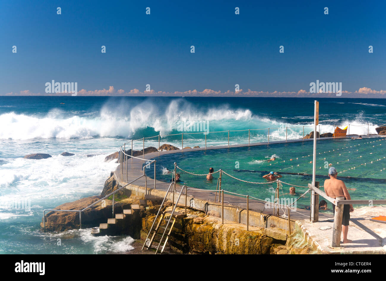 Bronte Bäder Oceanside Schwimmbad mit Schwimmer racing und Wellenrauschen im Hintergrund Bronte Sydney NSW Australia Stockfoto