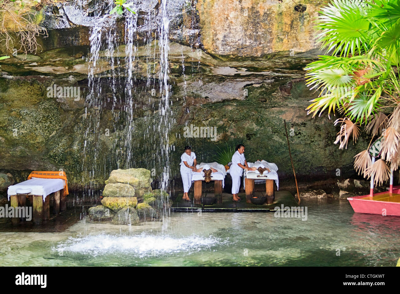 Besucher nach Xcaret genießen Sie eine Massage in einer Höhle hinter einem Wasserfall. Riviera Maya, Yucatan, Mexiko. Stockfoto