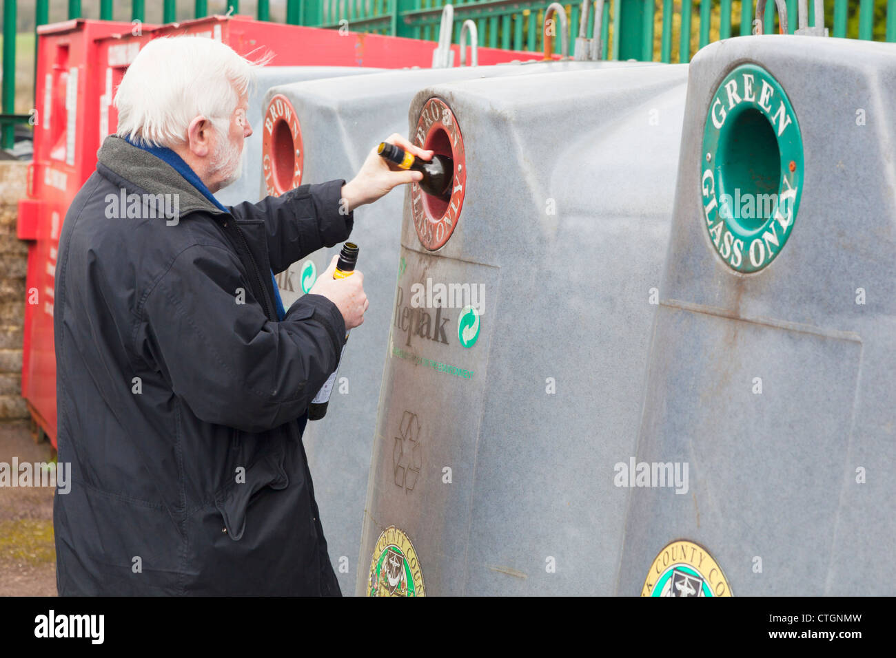 Dunmanyway, County Cork, Irland. Ältere Mann Tropfflaschen in Altglascontainer am Recyclinghof. Stockfoto