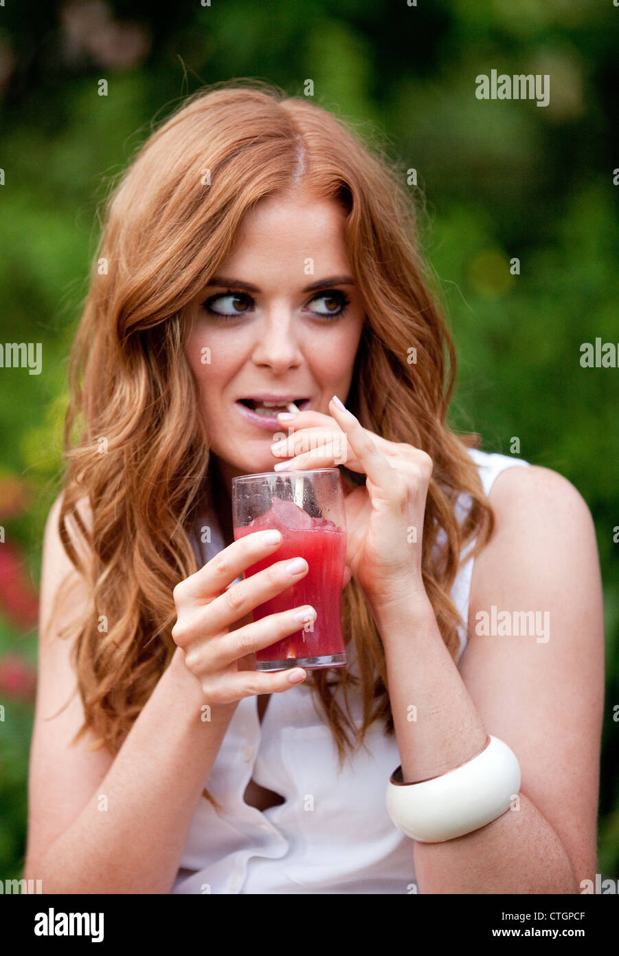 Attraktive junge rothaarige Frau trinkt einen Cocktail auf einer Party, UK Stockfoto