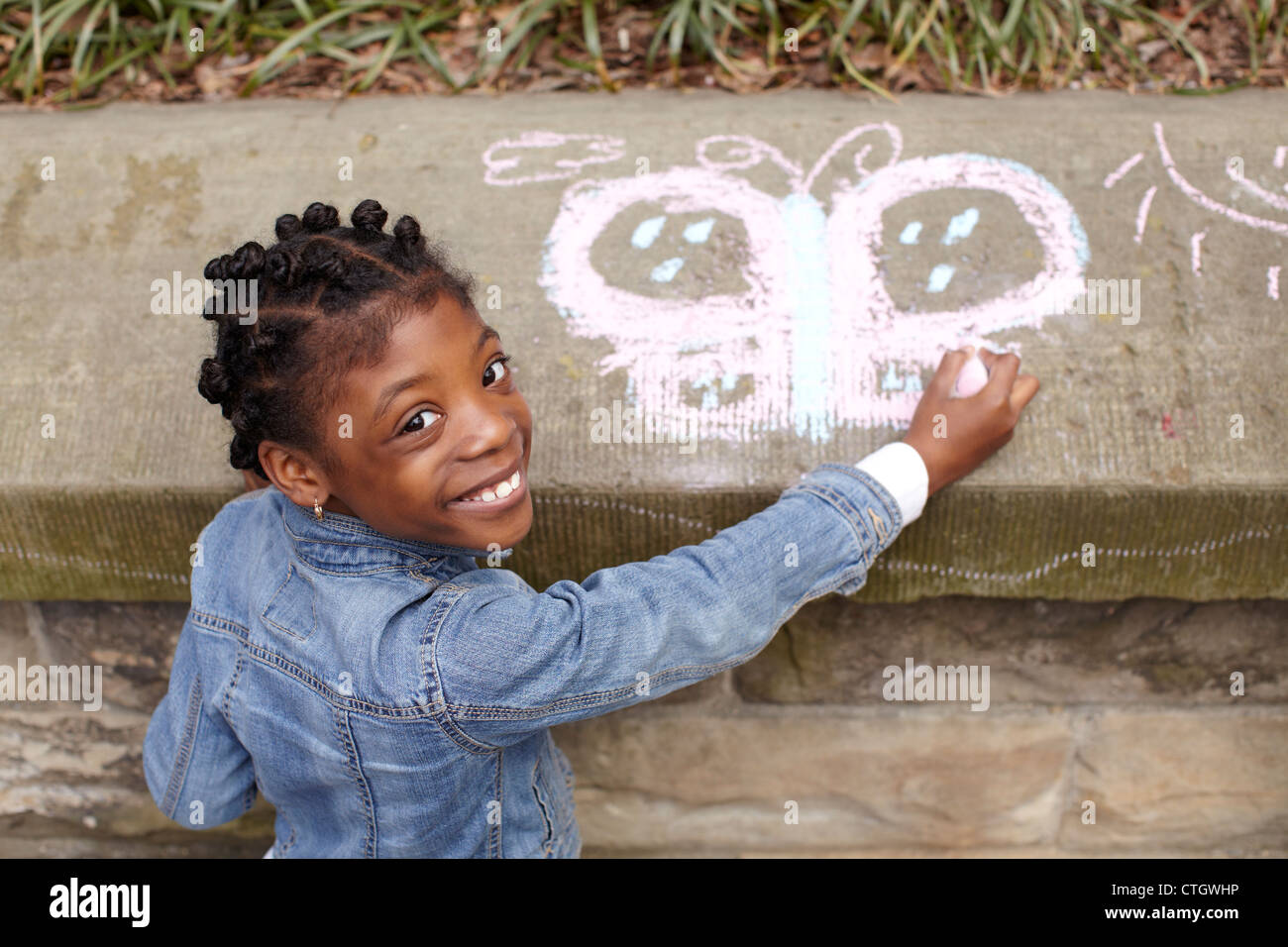 Gemischte Rassen Mädchen auf Zement mit Kreide zeichnen Stockfoto