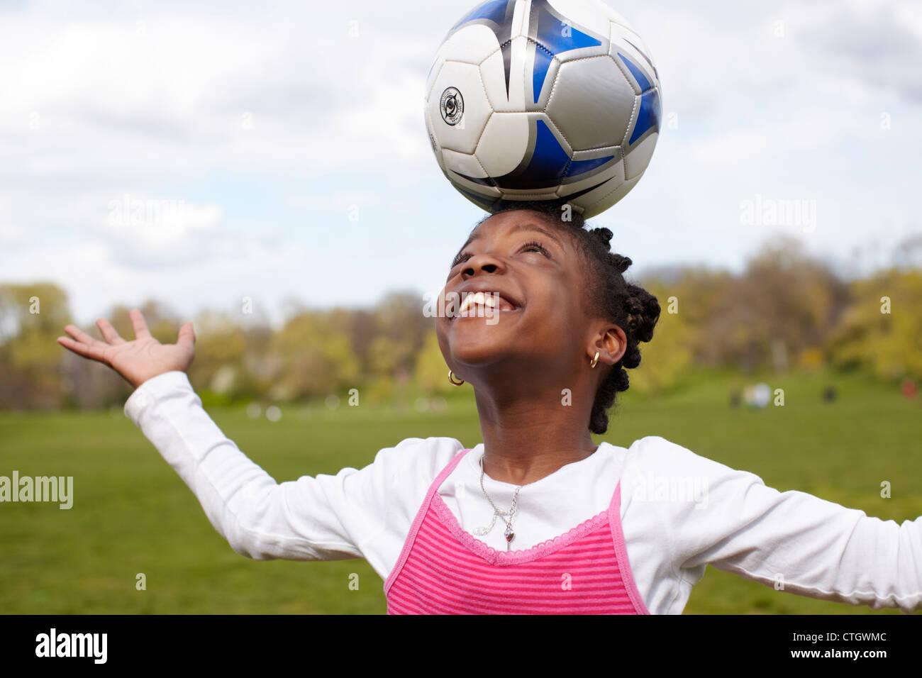Gemischte Rassen Mädchen Fußball auf Kopf balancieren Stockfoto