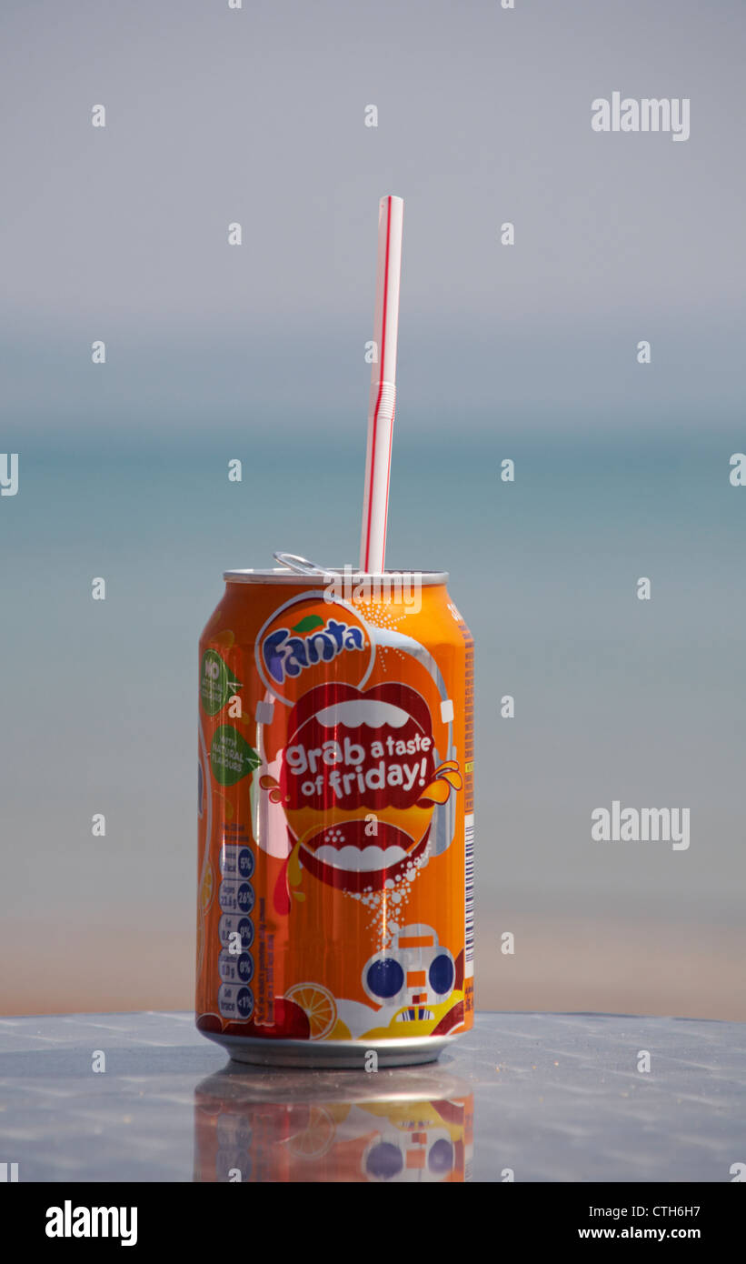 Genießen Sie eine Dose Fanta Orangengetränk am Meer in Weymouth, Dorset UK im Mai - Getränkekarte mit Plastikstroh Stockfoto