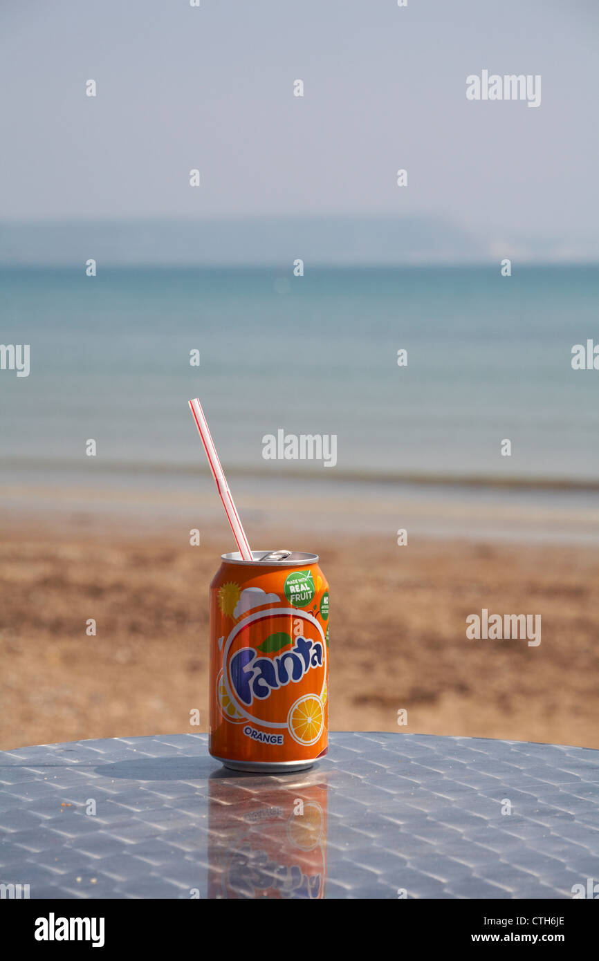 Genießen Sie eine Dose Fanta Orangengetränk am Meer in Weymouth, Dorset UK im Mai - Getränkekarte mit Plastikstroh Stockfoto