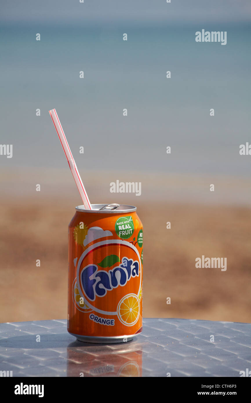 Genießen Sie eine Dose Fanta Orangengetränk am Meer in Weymouth, Dorset UK im Mai - Getränkekarte mit Plastikstroh Stockfoto
