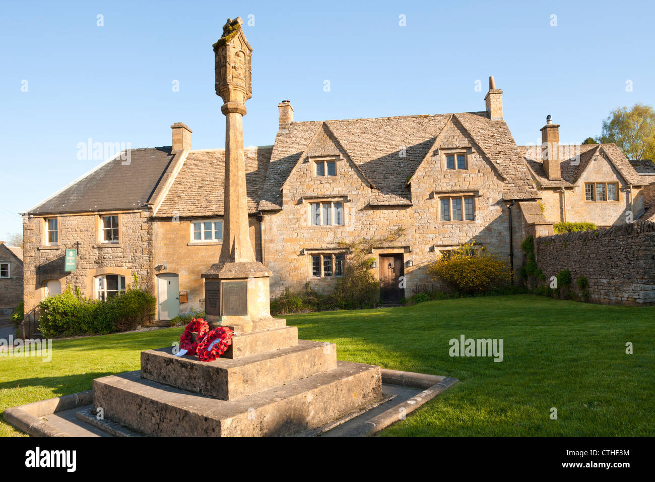 Abend-Sonnenlicht fällt auf das Kriegerdenkmal und Hütten in den Cotswold Dorf Guiting Power, Gloucestershire Stockfoto