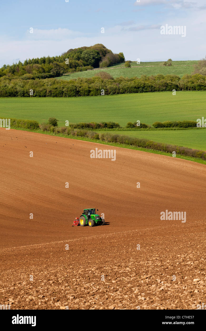 Ein Traktor und Drillmaschine Aussaat auf einem großen Feld von Cotswold brash Boden in der Nähe von Cotswold Dorf Hampen, Gloucestershire Stockfoto