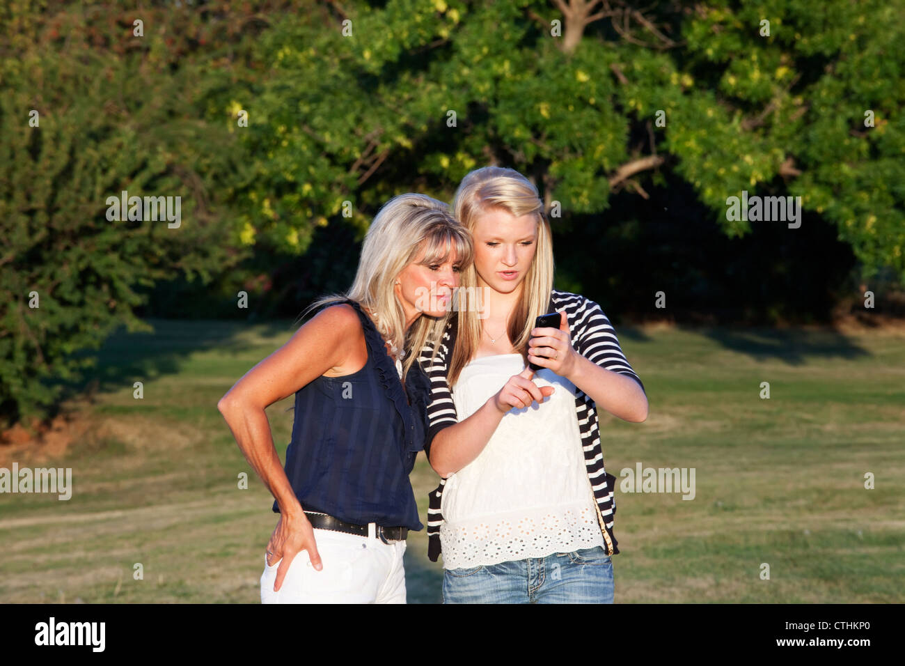 Mutter und Tochter In einem Park spazieren und Austausch von Textnachrichten zusammen; Edmonton, Alberta, Kanada Stockfoto