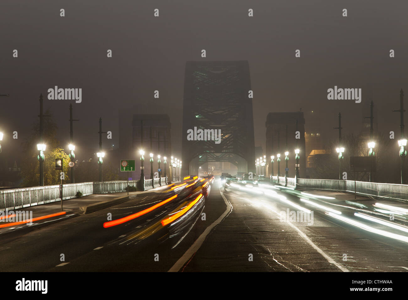 Licht-Strecken des Fahrzeug eingebauten Scheinwerfern und Rückleuchten an einer belebten Straße, die führt zu einer Brücke in der Nacht; Newcastle, England Stockfoto