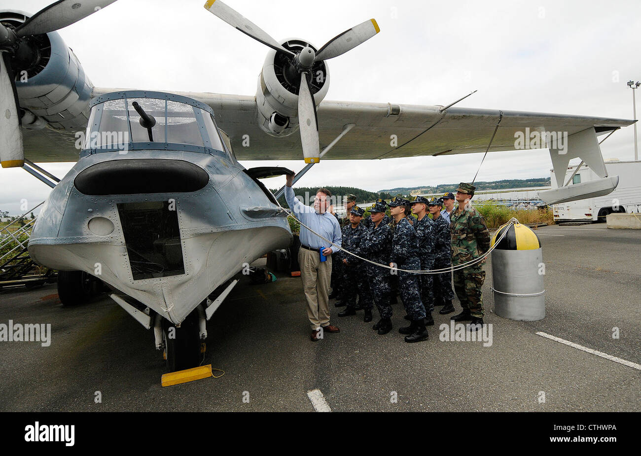 William R. Stein, Direktor der Operation für die Patrol Boat Consolidated (PBY) Memorial Foundation, erklärt einer Gruppe von Seekadetten während einer Führung am Naval Air Station Whidbey Island Seaplane Base, PBY Memorial Foundation Command Display, ein altes PBY. Stockfoto