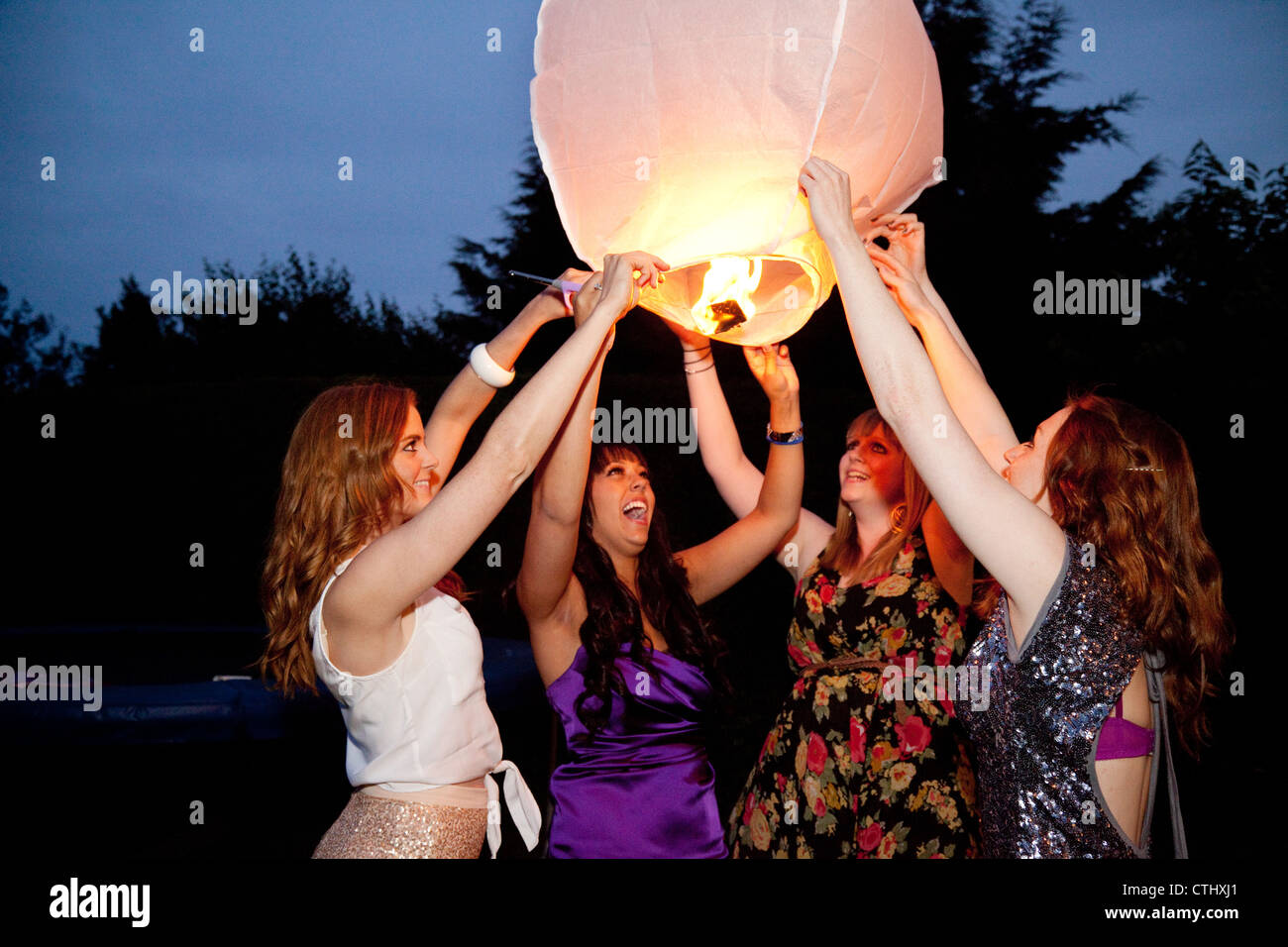 Vier junge Frauen, die Einführung einer Papierlaterne Himmel in der Nacht, UK Stockfoto