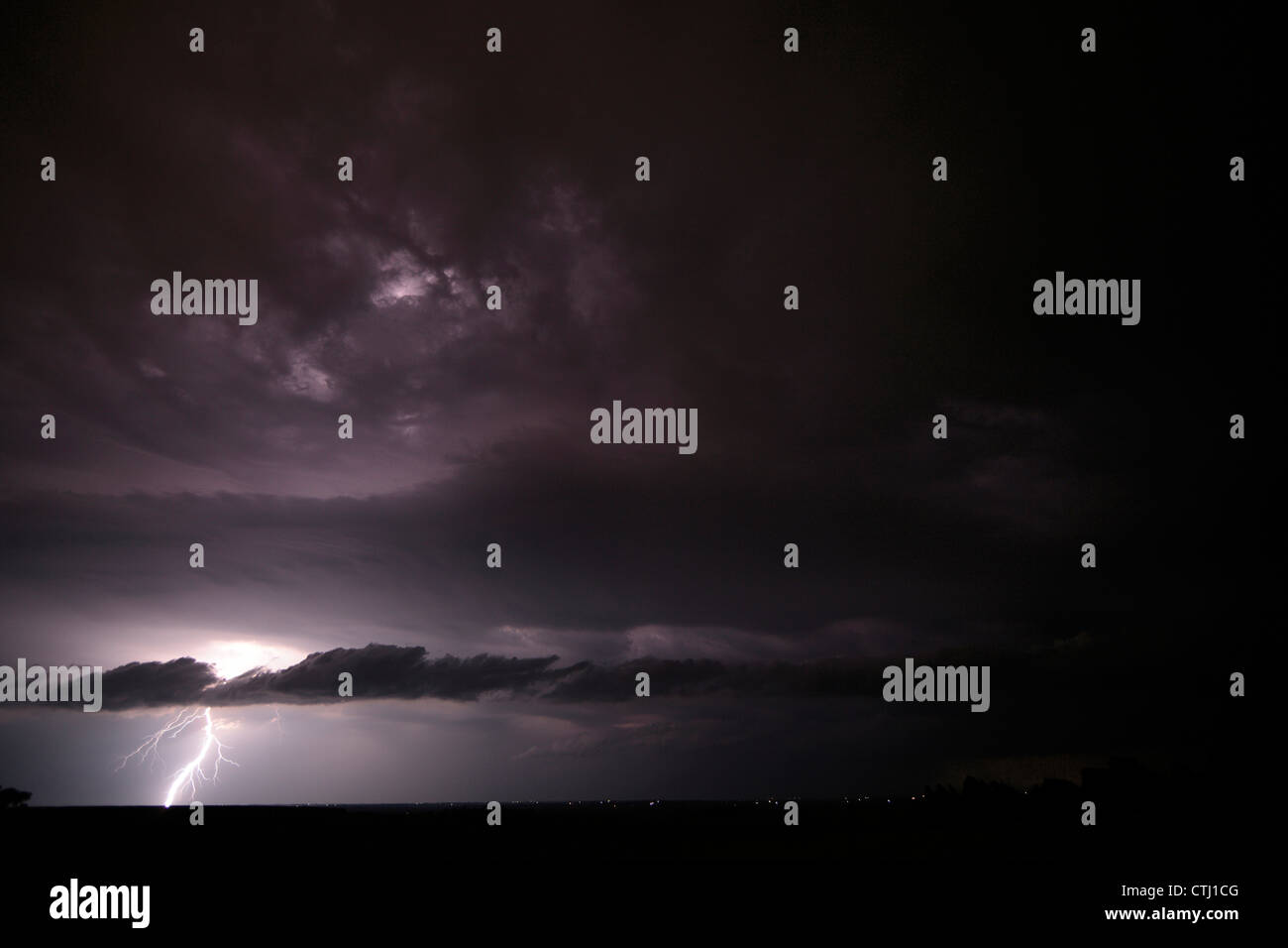 Ein Blitzeinschlag im Land leuchtet eine vielfältige Reihe von Wolken, einschließlich eine lange Scud Cloud. Nacht. Stockfoto