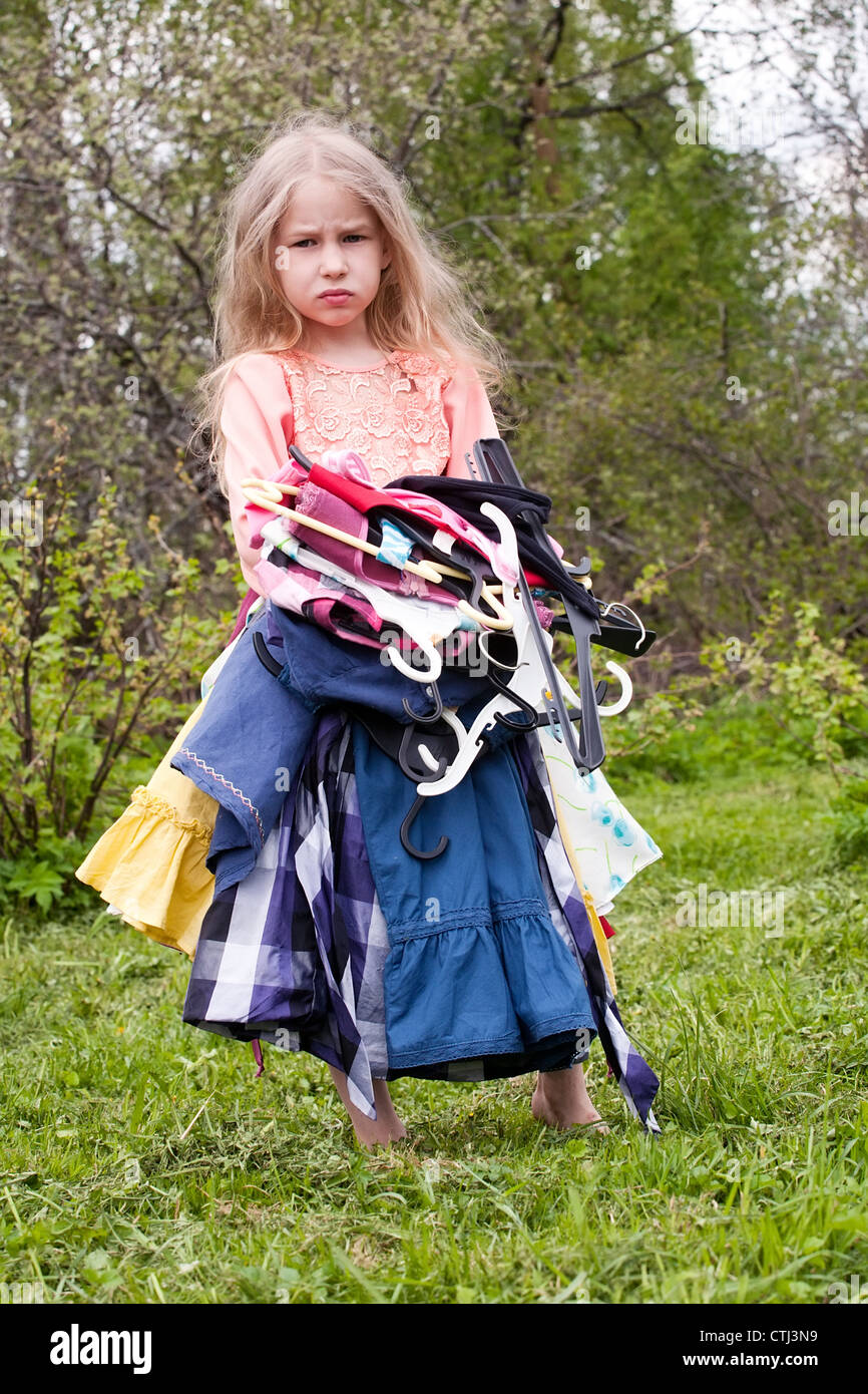 Trauriges Mädchen stehend mit Haufen von Kleidern in ihren Händen Stockfoto