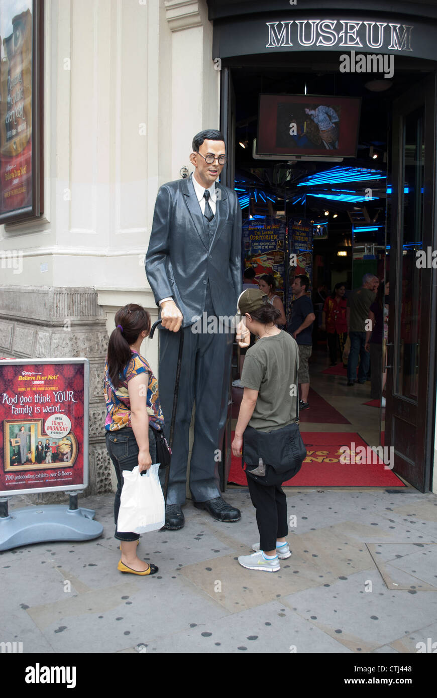 Touristen auf der Suche an der Statue von Robert Pershing Wadlow außerhalb Ripleys glauben es oder nicht! am Piccadilly Circus in London Stockfoto