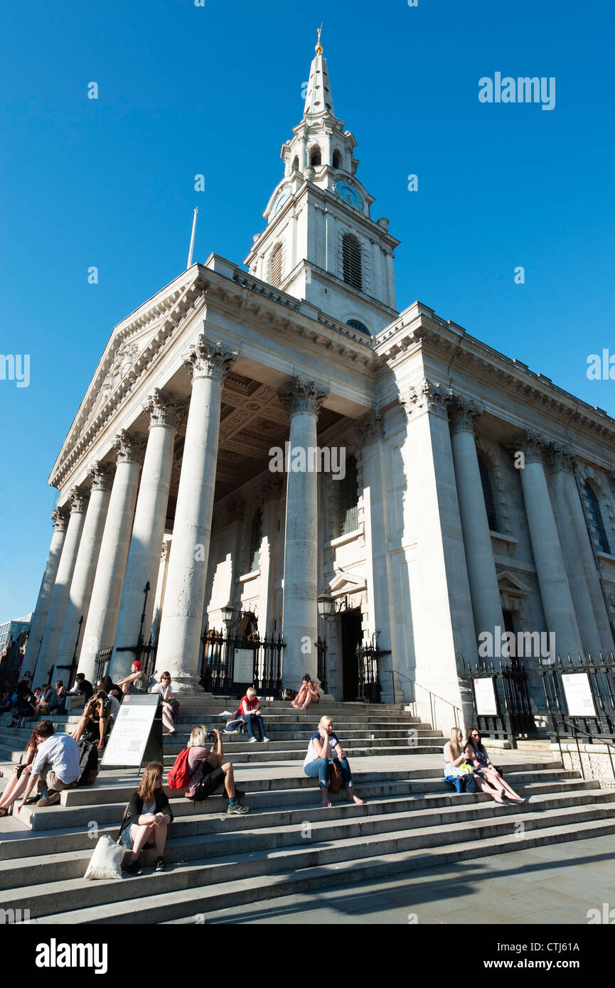 Touristen sitzen auf den Stufen vor St. Martin in the Fields, London, England Stockfoto