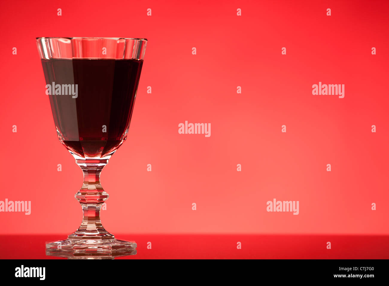 Glas Rotwein oder Likör auf rotem Grund Stockfoto
