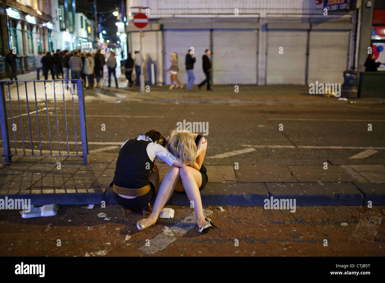 Eine junge Frau tröstet weinende Freundin an einem Samstagabend im Stadtzentrum von Cardiff, Wales, Großbritannien (UK). Stockfoto