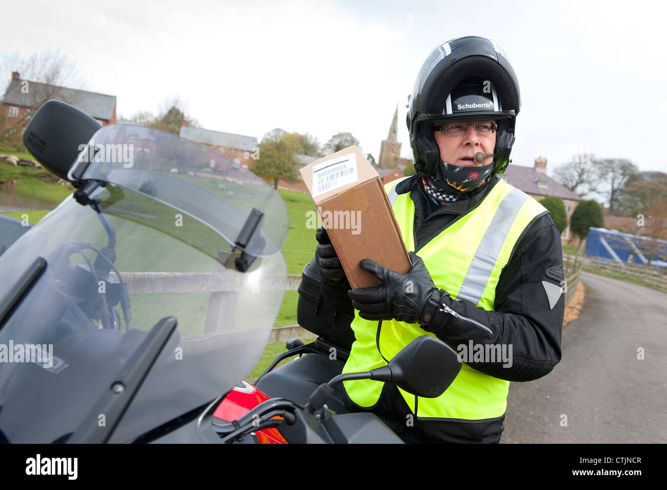 Motorrad Kurier liefert eine Paket im ländlichen Leicestershire, England. Stockfoto