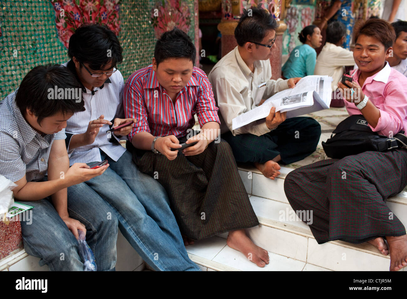 Junge burmesische Männer nutzen Mobiltelefone in der Shwedagon-Pagode in Yangon (Rangoon), Myanmar (Burma) Stockfoto