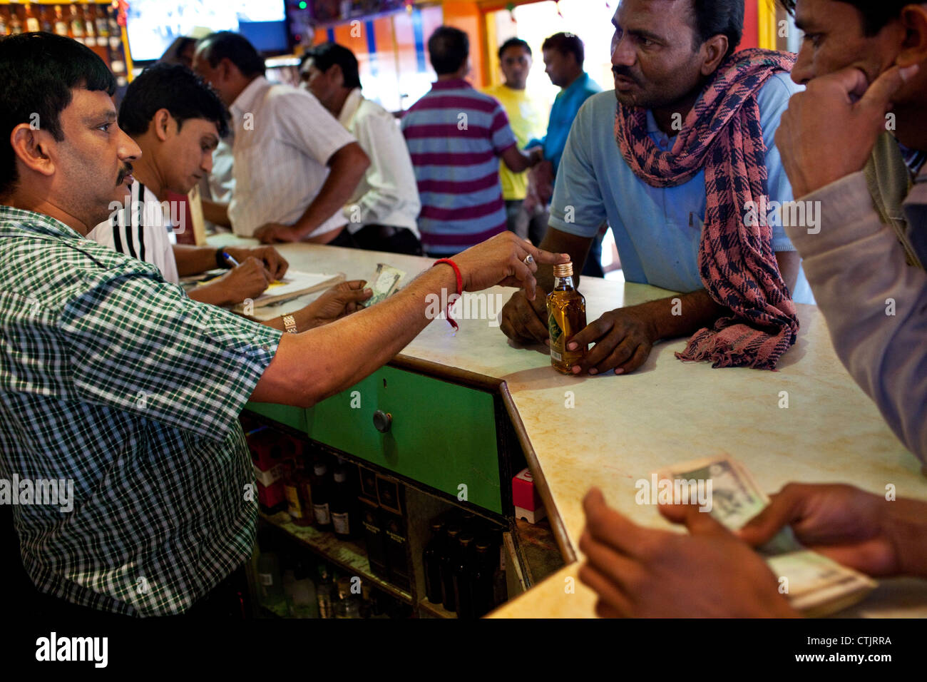 Kunden kaufen indische Alkohol (Whisky) in eine Spirituosen-Shop (Vinothek) in Nagoa Beach, Diu, Indien. Stockfoto