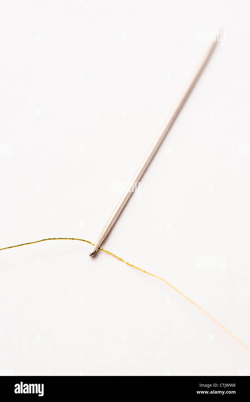 Nadel eingefädelt mit gold metallic Nähgarn Stockfoto