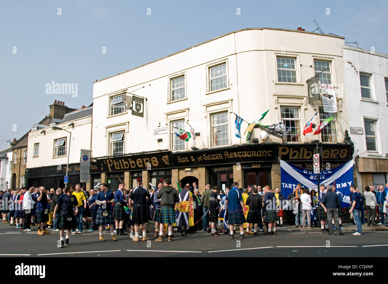 Schottische Fußball-Fans tragen Kilts und halten Flaggen außerhalb Phibbers Bar Schottland vs. Brasilien entsprechen Holloway Road London Stockfoto