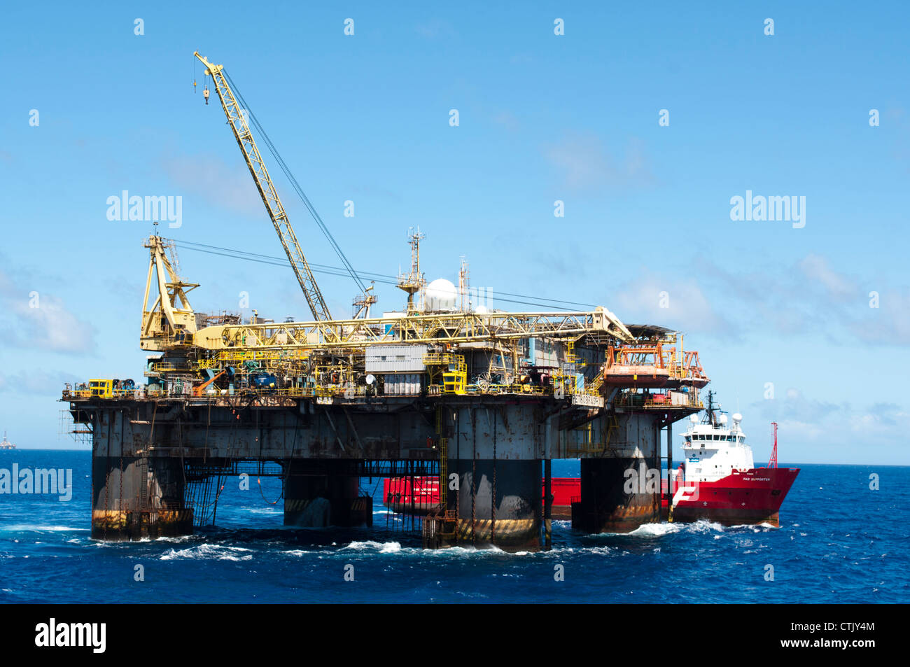 Öl-Rig PXX von Petrobras, mit Versorgungsschiff entlang Seite während Übertragungsvorgänge mit Kränen. Stockfoto