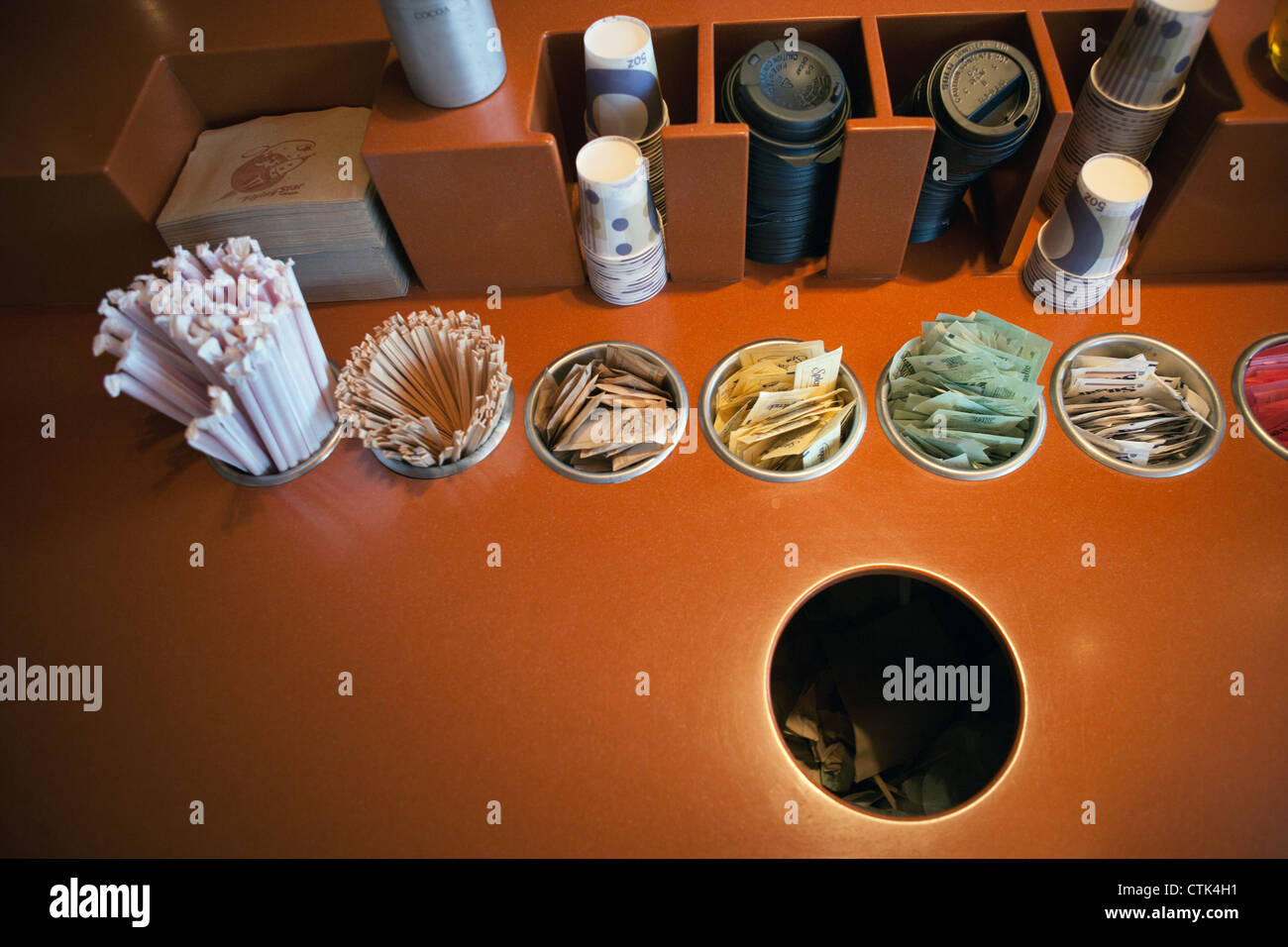 Ein Tisch in einem Café mit Zucker, Süßstoff, mitreißende Sticks und Cup Deckel. Stockfoto