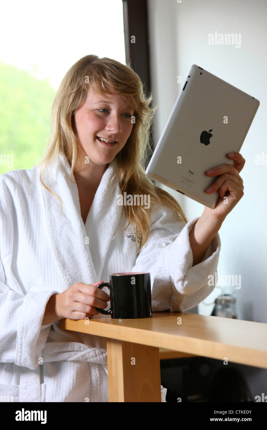 Junge Frau nutzt eine IPad, Tablet-Computer, Surfen im Internet, über Funkverbindung, am Morgen, nach einer Tasse Kaffee Stockfoto