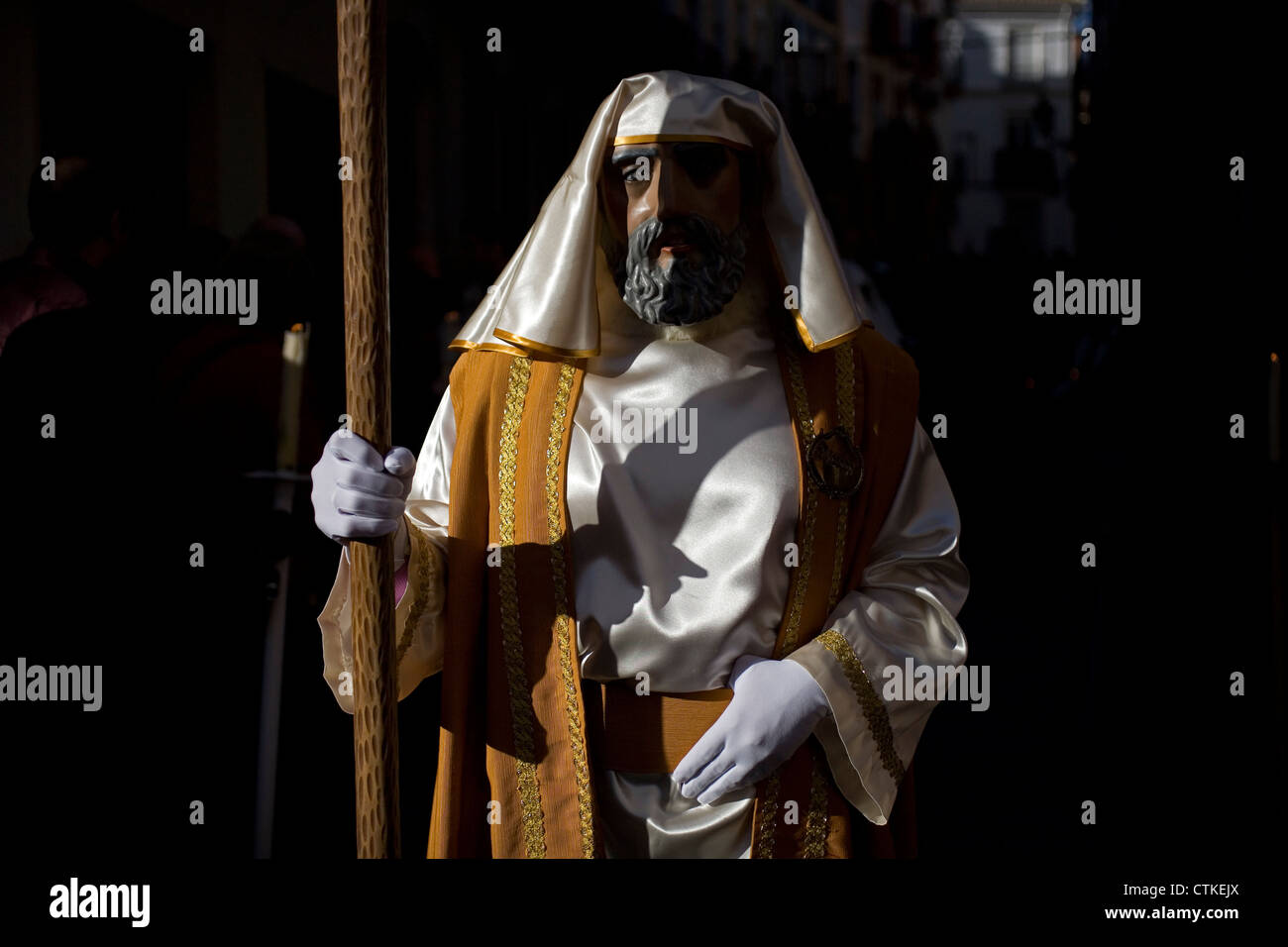 Ein maskierter Mann gekleidet wie eine biblische Figur mit einem Stab während einer Prozession der Karwoche in Puente Genil, Spanien geht Stockfoto