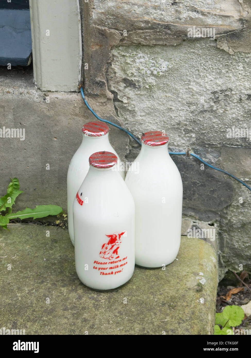 Traditionelle Milch Lieferung drei Flaschen Milch geliefert von einem Milchmann vor einer Haustür in einem Dorf in North Yorkshire Stockfoto