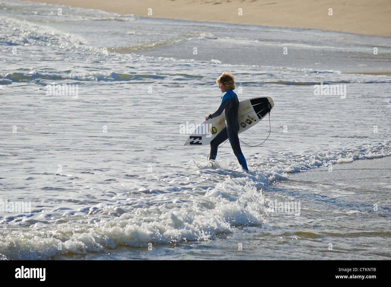 Ein junger Surfer sein Surfbrett mit in das Meer bei Margaret River Stockfoto