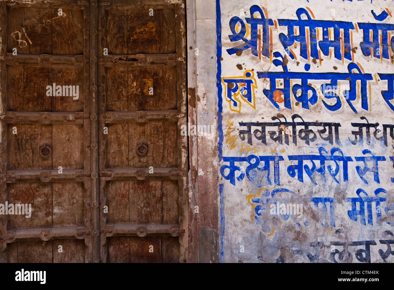 Holztür in Jodhpur mit Sanskrit schreiben an Wand Stockfoto