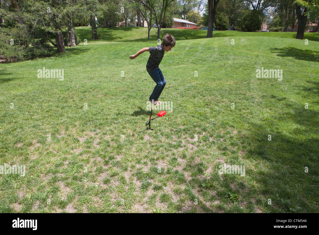 Zwölf Jahre alter Junge auf einer Pumpe Rakete springen Spielzeug in den Himmel in einem Park zu starten. Stockfoto